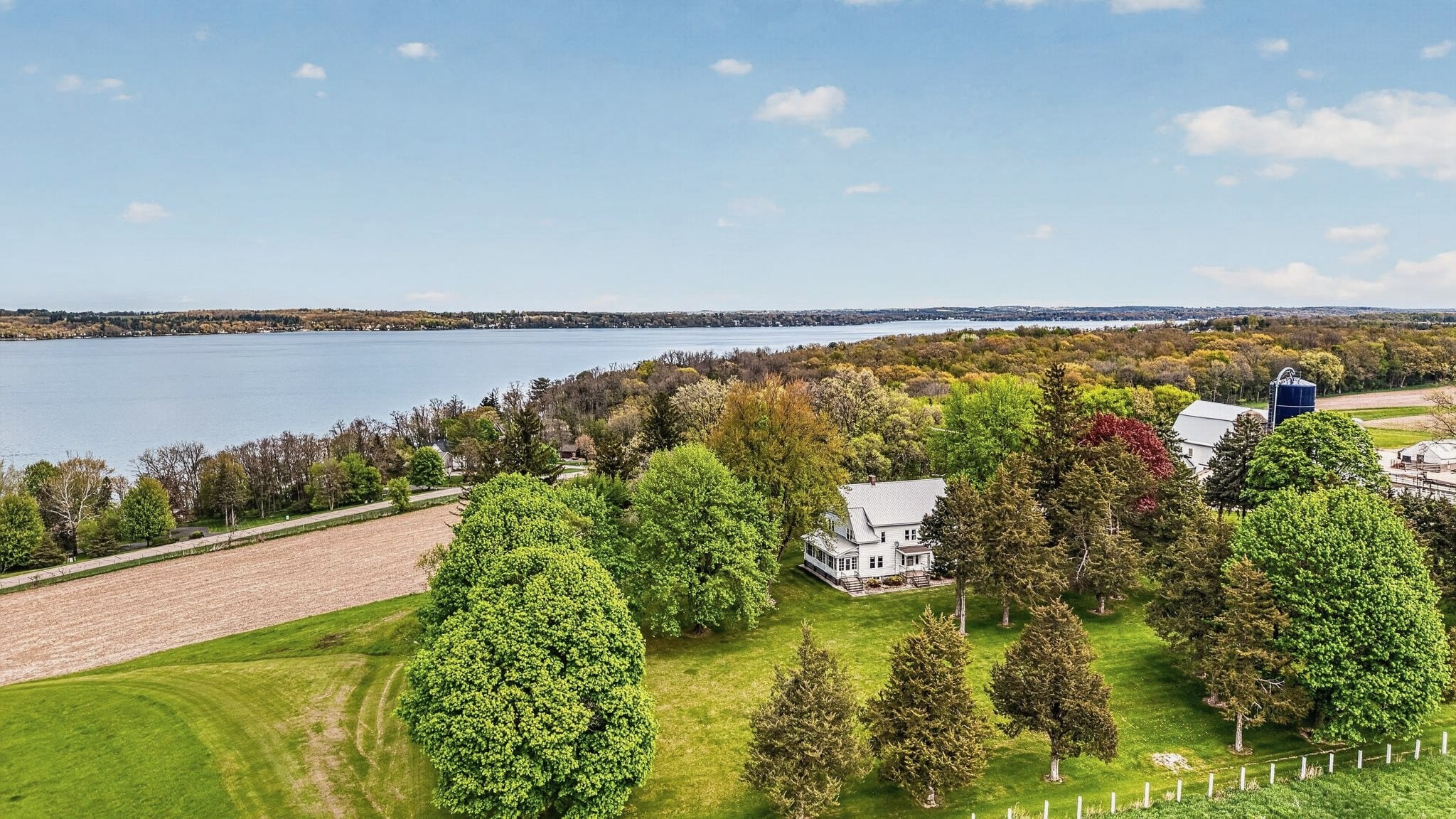 Drone view of Hilltop Haven with fields, trees and Green Lake behind.