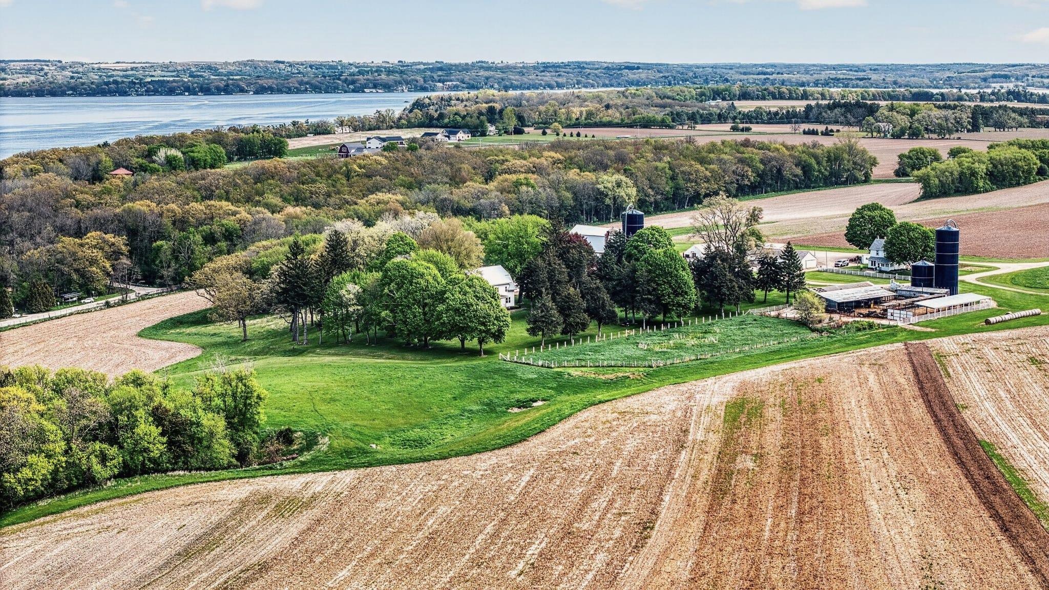 Drone view over farmland and trees near Markesan, Green Lake beyond.