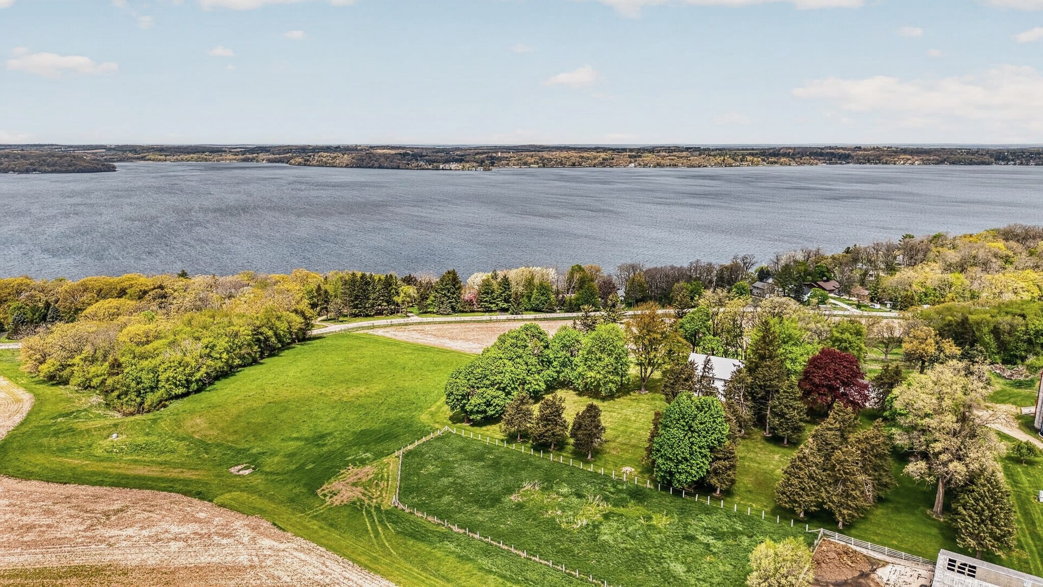Wide drone view of Green Lake, fields and trees in the foreground.