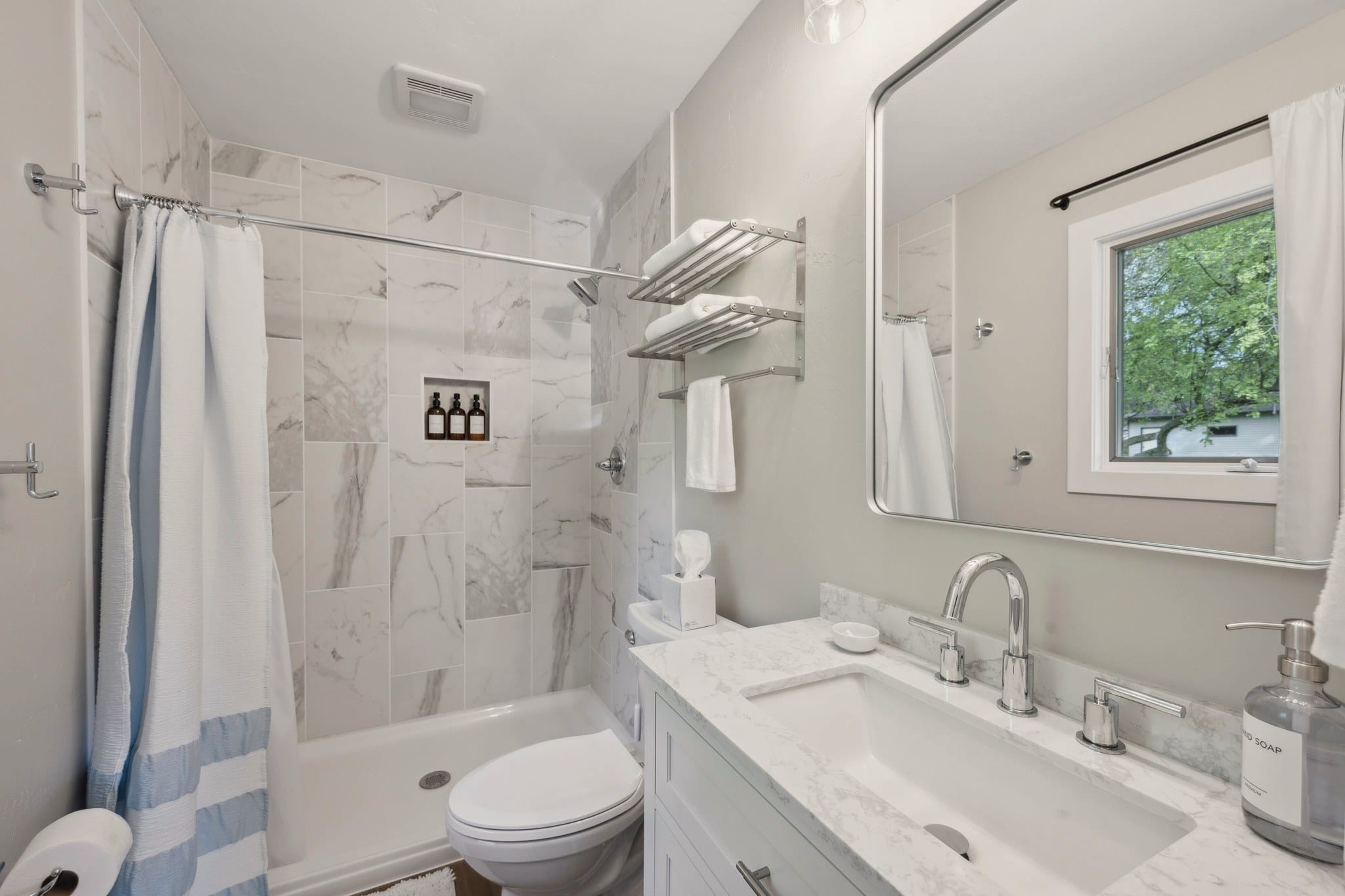 Serenity on Strauss bathroom with marble-look tile shower and white vanity.